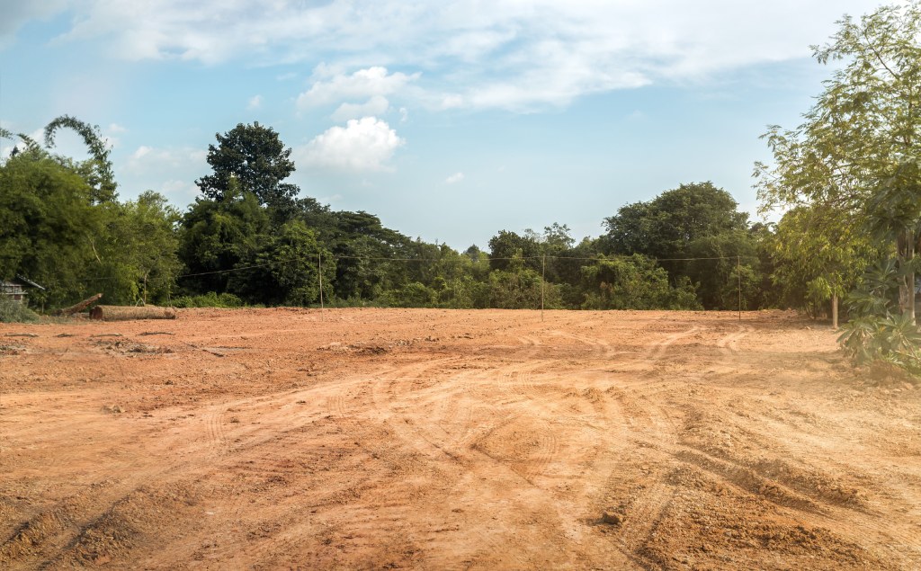 Cleared Construction Site with Graded Soil and Lush Greenbelt Border.jpg