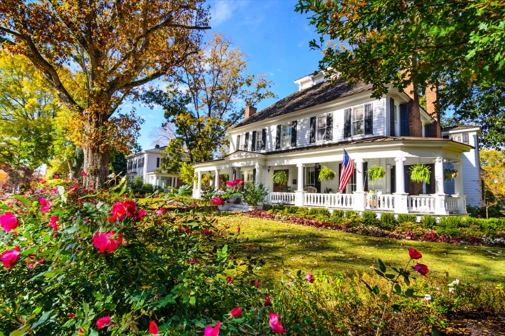 Historic White Colonial Home with Wrap around Porch American Flag and Autumn Landscaping.jpg